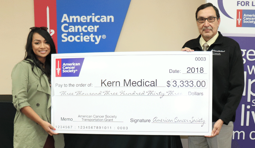 man and woman holding larger check